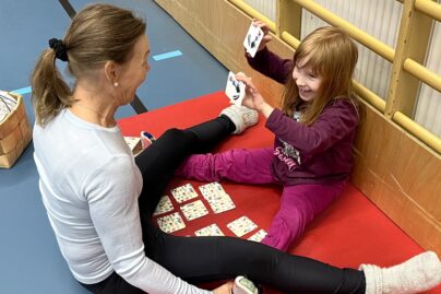 Fysioterapeutti ja lapsi istuvat jumppamatolla ja tekevät harjoitusta