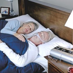 Iäkäs pariskunta nukkuu sängyssä ja miehellä on CPAP-laitteet.