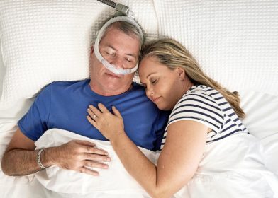 Pariskunta nukkuu sängyssä ja miehellä on CPAP-maski.
