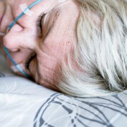Vaaleahiuksinen nainen nukkuu verenpaineen mittauslaitteet päällä.