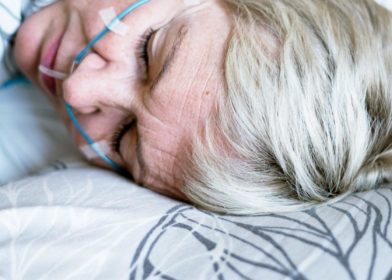 Vaaleahiuksinen nainen nukkuu verenpaineen mittauslaitteet päällä.