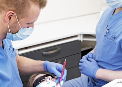 Hammaslääkäri ja hammashoitaja potilaan kanssa hoitohuoneessa