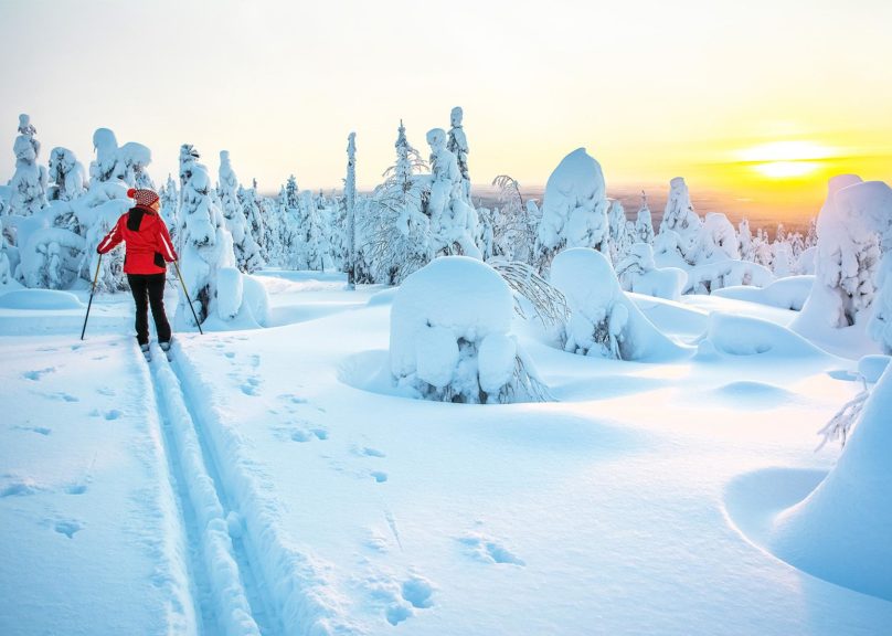 nainen hiihtamassa auringonlaskussa