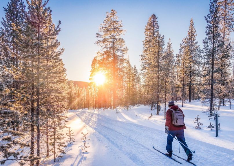 Mies hiihtää auringon paisteessa.