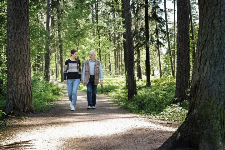 Nainen ja vanhempi mies kävelemässä metsässä.