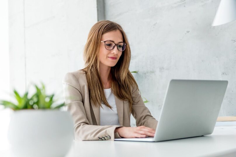 Nuori businessnainen kirjoittaa kannettavalla tietokoneella.